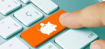 Finger der eine orangene Computertaste mit Sparschwein drückt