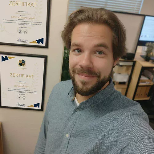 Mann mit Vollbart und braunen Haaren im blauen Pullover