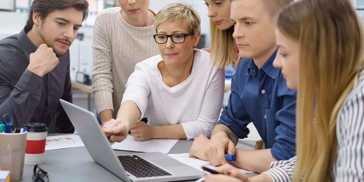 Geschäftsfrau erklärt jungen Kollegen etwas am PC