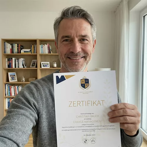 Mann mit braunen Haaren in grauer Jacke und dunklem Shirt