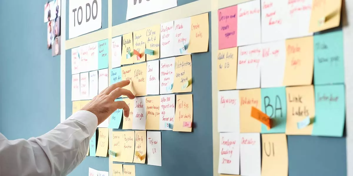 Hand eines Mannes an einem Task Board im Büro