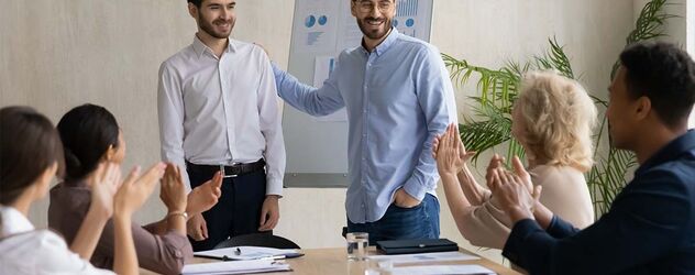 Glücklicher junger Geschäftsmann stellt dem Team einen neuen männlichen Angestellten vor.