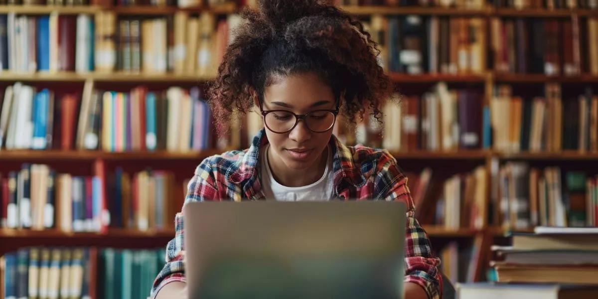 Studentin sitzt an einem Laptop in einer Bibliothek
