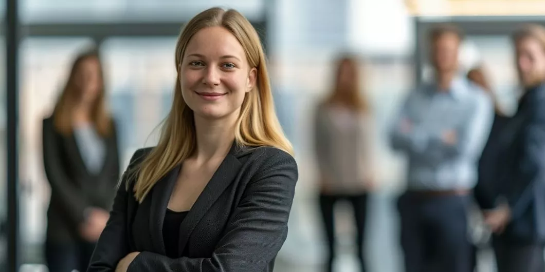 eine Businessfrau steht im Daily Standup vor ihrem Team und lächelt in die Kamera