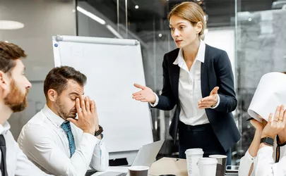 weibliche Managerin oder Teamleiterin, die während einer Konferenz im Besprechungsraum mit den Mitarbeitern diskutiert