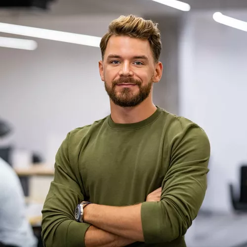 Mann mit braunen Haaren, Vollbart und grünem Pullover