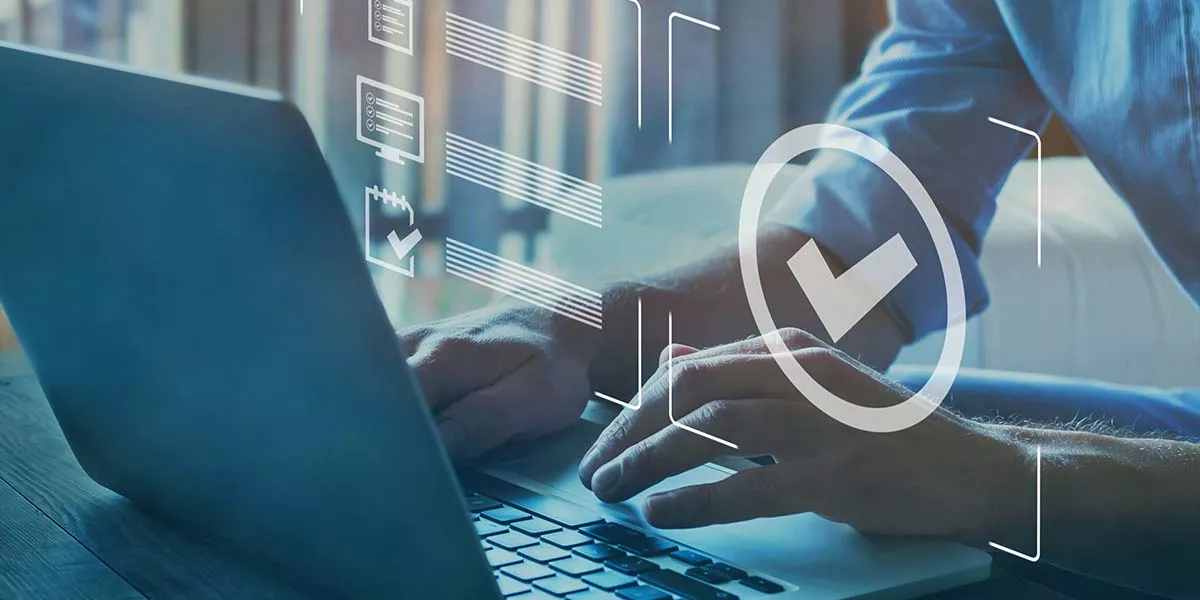 ein Mann sitzt an einem Laptop und arbeitet und eine virtuelle Grafik zeigt eine Liste mit Häkchen an