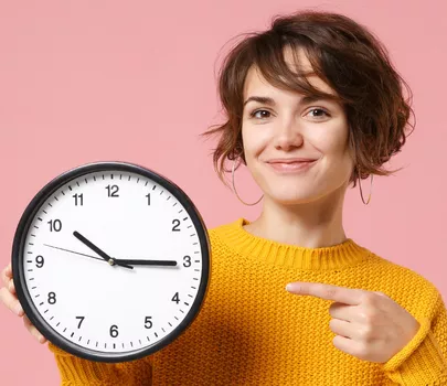 Frau zeigt auf eine große Uhr in ihrer Hand