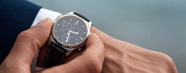 ein Mann in einem Geschäftsanzug, der eine Armbanduhr an seiner Hand überprüft