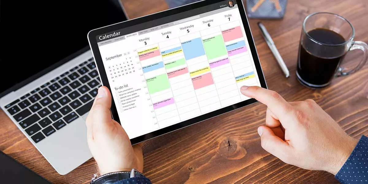Mann benutzt Kalender-App auf Tablet bei der Arbeit
