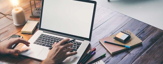 Nahaufnahme von männlichen Händen an der Tastatur eines Laptop mit leerem Bildschirm
